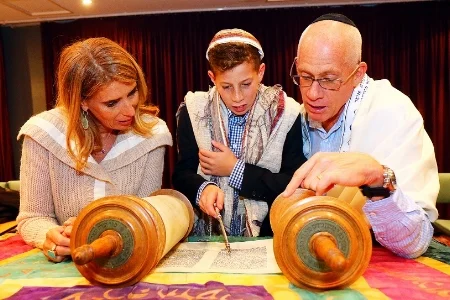Family gathered around a Torah scroll at Shira